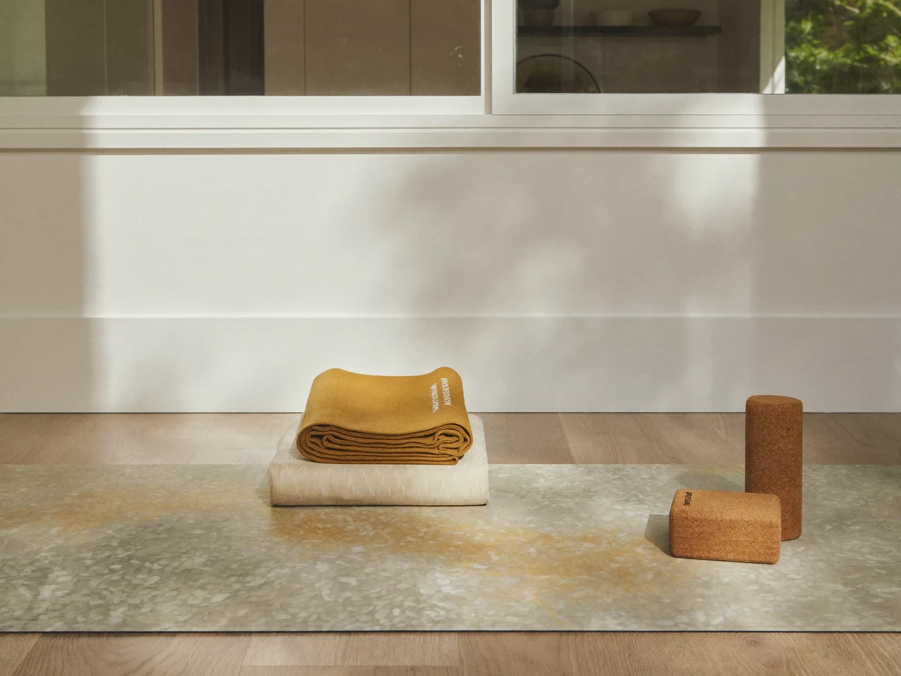Angolo yoga luminoso con tappetino su pavimento in rovere, blocco in sughero e coperta