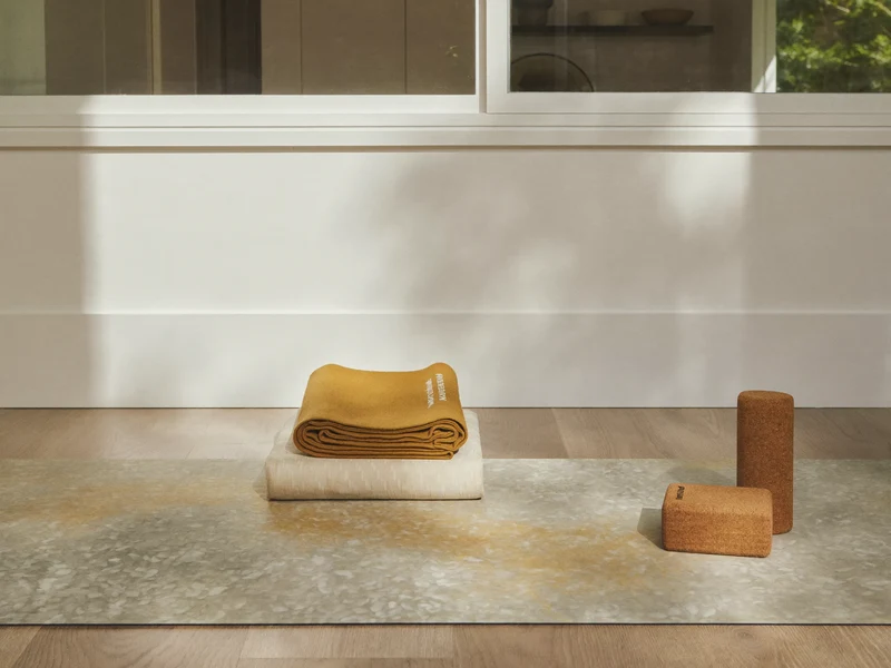 Angolo yoga luminoso con tappetino su pavimento in rovere, blocco in sughero e coperta